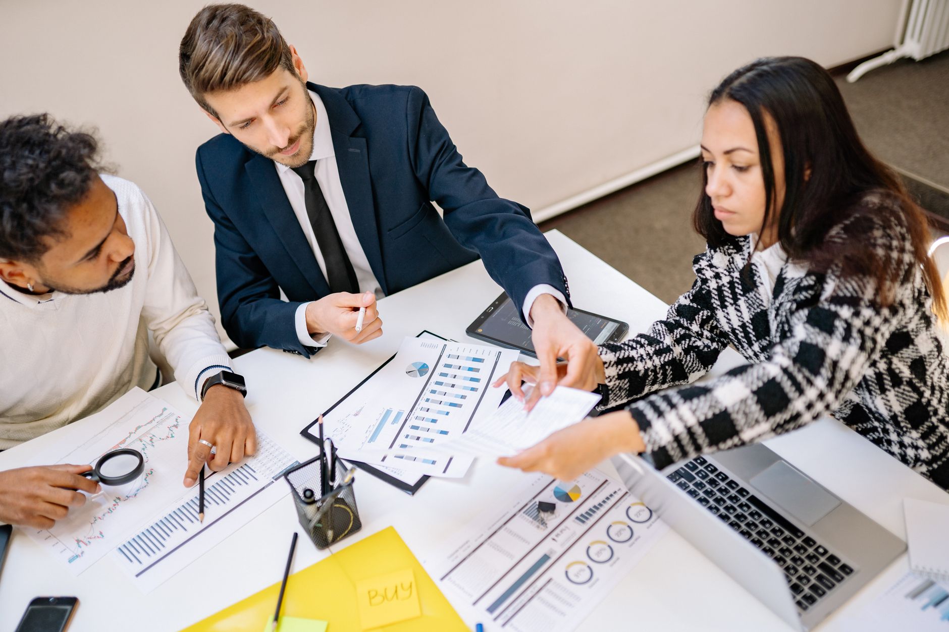 A team discussing a business proposal around a table in a meeting room, reflecting the business management stream's focus on commercial analysis and leadership